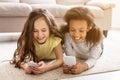 Little friends playing on smartphones, lying on floor