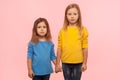 Little friends. Two cute charming preschool girls in sweatshirts standing together, holding hands