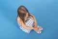 A  little frustrated or offended girl with pout lips sits on blue background in studio, top view Royalty Free Stock Photo