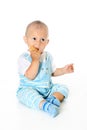 Little funny baby boy holds and eats cookies