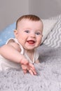 Little funny baby in white laughs on bed with pillows Royalty Free Stock Photo