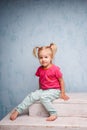 Little funny blue-eyed girl child blonde with a haircut two ponytails on her head sitting on a gossip on the background of an old Royalty Free Stock Photo