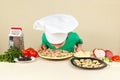 Little funny boy in chefs hat sniffing cooked pizza Royalty Free Stock Photo