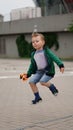 Little funny boy jumps on the square with gray pavement