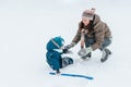 Little funny boy skating in the park and fell with his mother. Learn to Play ice hockey with stick. Outdoor. Winter Royalty Free Stock Photo