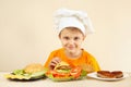 Little funny chef puts cheese on hamburger