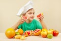 Little funny chef with two slices of grapefruit at table with fruits Royalty Free Stock Photo