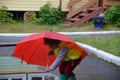 little funny cute girl walks in the rain with a red umbrella, in green rubber boots through the puddles. Laughs, has fun Royalty Free Stock Photo