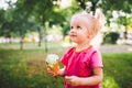 Little funny girl blonde eating sweet blue ice cream in a waffle cup on a green summer background in the park. smeared her face an Royalty Free Stock Photo