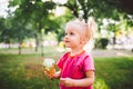 Little funny girl blonde eating sweet blue ice cream in a waffle cup on a green summer background in the park. smeared her face an Royalty Free Stock Photo