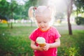 Little funny girl blonde eating sweet blue ice cream in a waffle cup on a green summer background in the park. smeared her face an Royalty Free Stock Photo