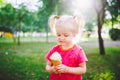 Little funny girl blonde eating sweet blue ice cream in a waffle cup on a green summer background in the park. smeared her face an Royalty Free Stock Photo