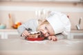 Little funny girl with chef hat eating cake Royalty Free Stock Photo