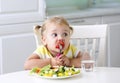 Little funny girl eating fresh vegetables. Small caucasian kid have a lunch home Royalty Free Stock Photo