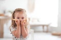 A little funny girl holds a cookie near face and laughs. Portrait of a child in bright colors