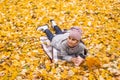 Little funny girl lies on yellow leaves in the forest. Child on a walk in the autumn park. Preschool girl Royalty Free Stock Photo