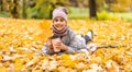 Little funny girl lies on yellow leaves in the forest. Child on a walk in the autumn park. Preschool girl Royalty Free Stock Photo