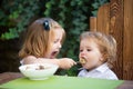 Little funny girl sister feeding baby. Cute funny babies eating, baby food, Healthy kids breakfast. Good appetite. Royalty Free Stock Photo