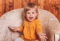 Little funny girl sits in a chair and holds a cereal loaf in her hand