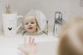 reflection in the mirror of a little funny girl washing hands and face in the bathroom Royalty Free Stock Photo