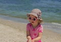 Little funny girl 3 years old at the sea in pink sunglasses.