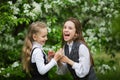 Little funny girls in stylish school uniforms play outdoors in the blossoming apple park