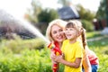 Little gardener girl with mother watering on lawn near house Royalty Free Stock Photo