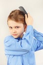 Little gentleman in a bright shirt brushing her hair hairbrush Royalty Free Stock Photo