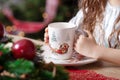 Little giirl hands keeping a cupof tea  standing on the table. Christmas and New Year. Winter holidays concept Royalty Free Stock Photo