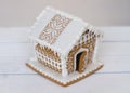 Little gingerbread house with glaze over defocused lights of Christmas decorated fir tree. Royalty Free Stock Photo