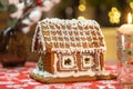 Little gingerbread house with glaze standing on table with tablecloth and decorations, candles and lanterns. Living room Royalty Free Stock Photo