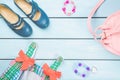 Little girl accessories. Pink bag with colorful dress, circlet, hair ties and shoes on blue pastel wooden background. Top view Royalty Free Stock Photo