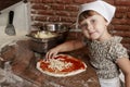 Little girl adding cheese to pizza.