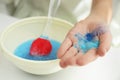 Little girl adding colored sparkles to slime toy at table, closeup