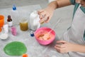 Little girl adding colored sparkles to homemade slime toy at table