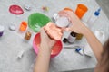 Little girl adding decorative balls to homemade slime toy at table