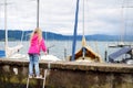 Little girl admiring beautiful yachts in a harbor of Lindau, a town on the coast of Bodensee lake in Germany on cloudy autumn day Royalty Free Stock Photo
