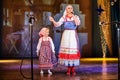 A little girl and an adult woman in Russian national dress rehearsing on stage. Mother and daughter sing and dance together Royalty Free Stock Photo