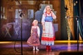 A little girl and an adult woman in Russian national dress rehearsing on stage. Mother and daughter sing and dance together Royalty Free Stock Photo