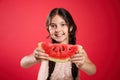 Cute little girl against red background, focus on hands with watermelon