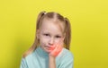 A little girl aged seven years old holds her cheek with her hands on a yellow background. Concept of tooth pain in