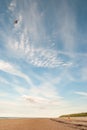 Little girl alone on a beach flying her kite in a beautiful blue sky Royalty Free Stock Photo