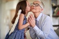 A little girl with angel wings is kissing and exchanging emotions with her grandmother at home. Family, home, love, playtime Royalty Free Stock Photo