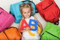 Little girl anxious to go to school - lying on the floor among c Royalty Free Stock Photo