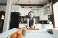A little girl in an apron and a chef& x27;s hat is rolling out cookie dough, laughing. Royalty Free Stock Photo