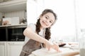 Little girl in an apron makes drawings on the dough in the kitchen, smiling at the camera. Royalty Free Stock Photo