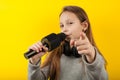 Little girl artist, talent show. Sings a song into the microphone. Portrait on a yellow background