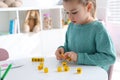 Little girl assembling word with bricks in classroom at English lesson