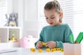 Little girl assembling word with yellow bricks in classroom at lesson