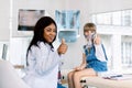 Little girl with asthma problems making inhalation with mask on her face. Young African woman doctor helps the little Royalty Free Stock Photo